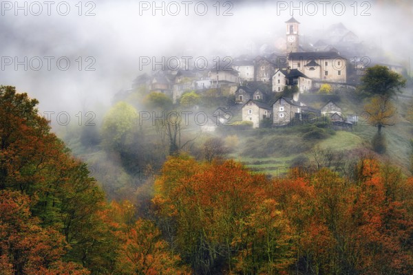Village view of Corippo in the fog surrounded by autumn-coloured deciduous trees, Verzasca Valley, Canton Ticino, Switzerland, Europe