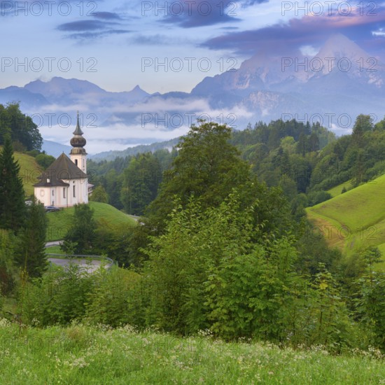 Maria Gern church in a picturesque mountain landscape, surrounded by dense green vegetation and rolling hills in the morning mist, Berchtesgaden, Bavaria, Germany, Europe