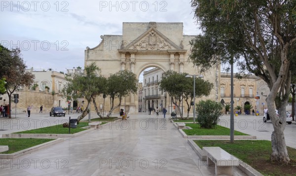 Spacious square with historic Tor tor and trees, bustling with people in an urban ambience, Porta Napoli, Lecce, Apulia, Italy, Europe