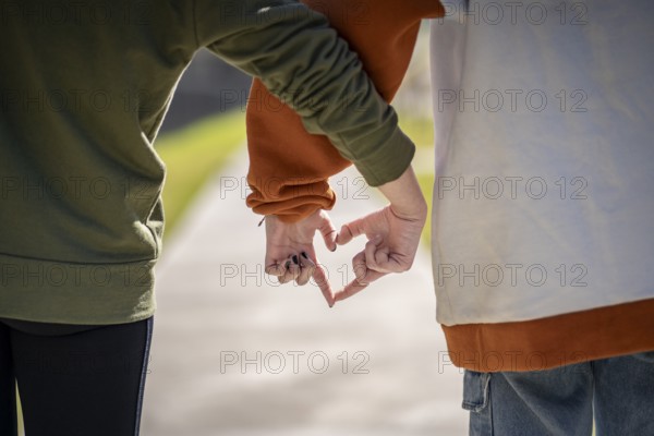 Two girls holding hands making a heart