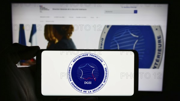 Stuttgart, Germany, 11-27-2023: Person holding mobile phone with logo of Direction Générale de la Sécurité Intérieure (DGSI) in front of web page. Focus on phone display, Europe