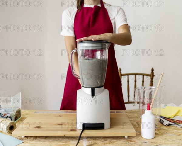 Midsection view woman grinding paper pulp mixer