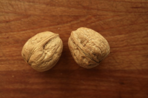 Two walnuts on a golden wood aged table