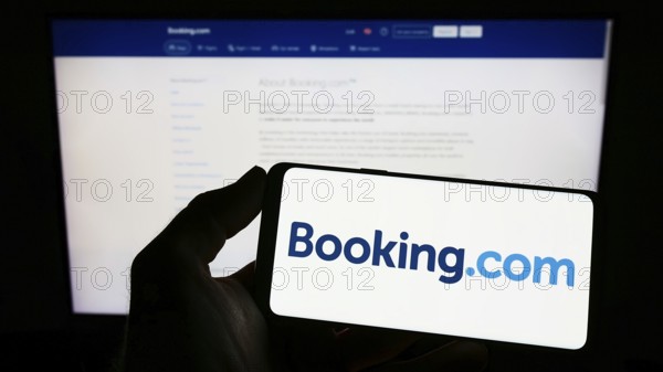 Stuttgart, Germany, 10-24-2022: Person holding smartphone with logo of Dutch online travel agency Booking.com on screen in front of website. Focus on phone display, Europe
