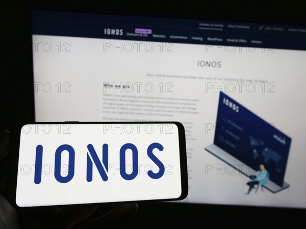 Stuttgart, Germany, 01-21-2023: Person holding cellphone with logo of German web hosting company Ionos SE on screen in front of business webpage. Focus on phone display, Europe