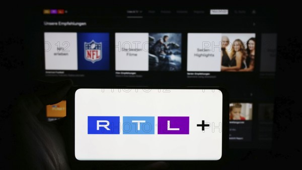 Stuttgart, Germany, 02-13-2024: Person holding cellphone with logo of German entertainment platform RTL plus in front of business logo. Focus on phone display, Europe