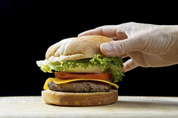 Putting the top bun on a delicious cheeseburger in a studio setting