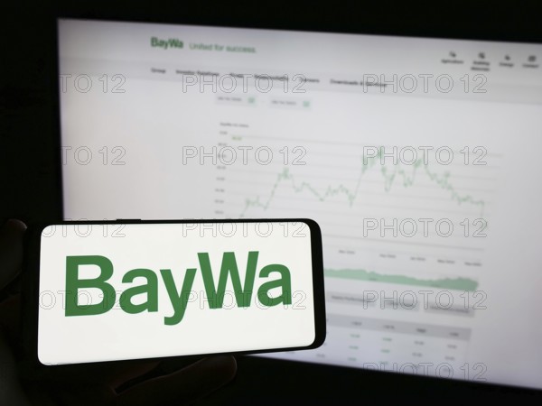 Stuttgart, Germany, 09-14-2023: Person holding mobile phone with logo of German agribusiness company BayWa AG on screen in front of business web page. Focus on phone display, Europe