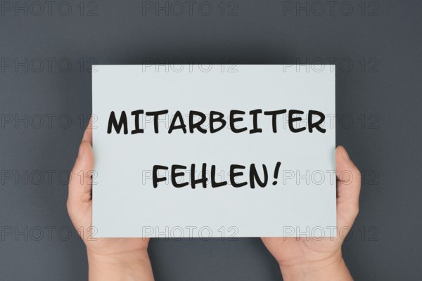 The words shortage of employees are standing in german language on the paper, skilled workers are missing
