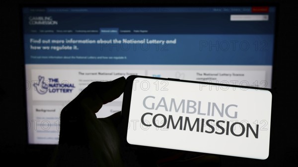Stuttgart, Germany, 04-01-2023: Person holding cellphone with logo of British public body Gambling Commission on screen in front of webpage. Focus on phone display, Europe
