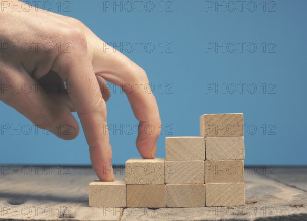 Hand of a businessman taking the next step on wooden stairs, motivation or career concept