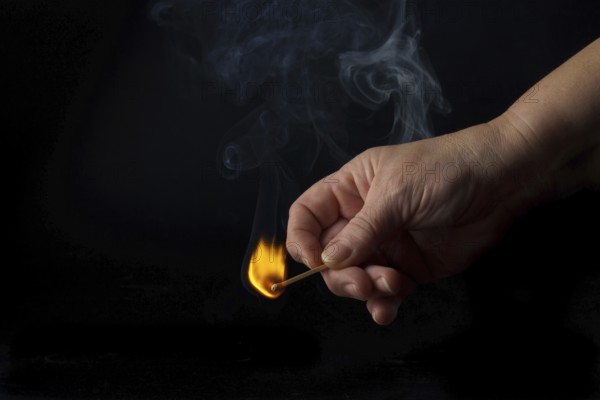 Close-up of a woman's hand lighting a match isolated on black background