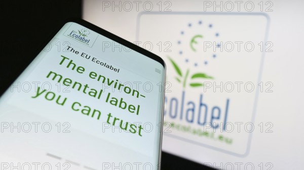 Stuttgart, Germany, 03-12-2023: Mobile phone with webpage of environmental certification EU Ecolabel on screen in front of logo. Focus on top-left of phone display, Europe