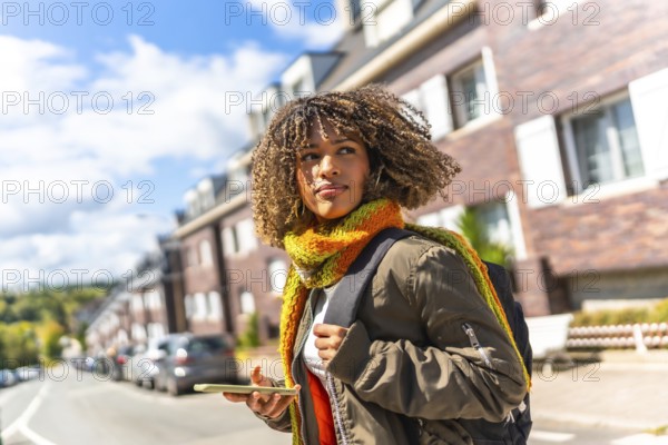 Brunette beauty girl with casual warm clothes using phone in the street in a cold day