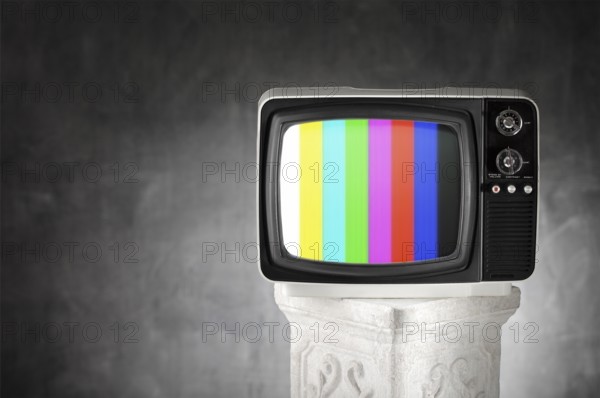 Old television with color bars on a plaster column