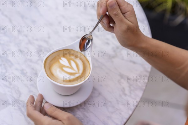 Top view of a woman about to drink a perfect coffee cup in an outdoor terrace