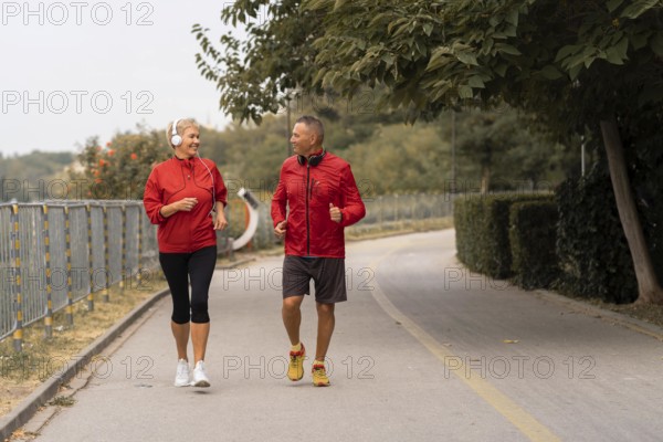 Front view senior couple jogging together outside park