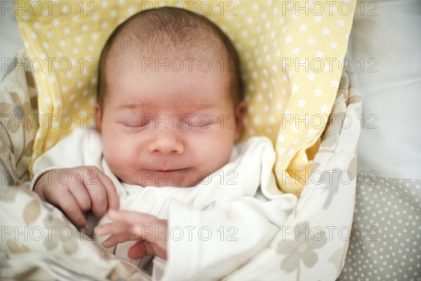 Cute newborn baby sleeping in swaddle wrap with smile on her face. Newborn theme