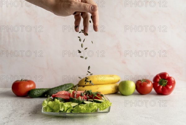 Person s hand sprinkling pumpkin seeds vegetable salad