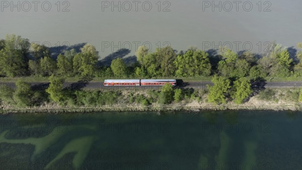 A red local railway runs on an embankment between two bodies of water with different colours, drone shot, Upper Bavaria, Bavaria, Germany, Europe