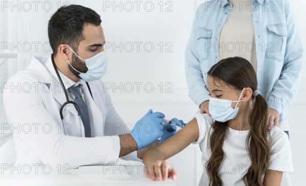 Male doctor vaccinating little girl that s supported by her mother