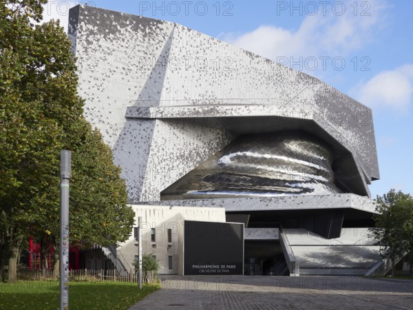 Modern architecture with a metallic façade and unusual shape under a cloudy sky. Philharmonie de Paris. Paris