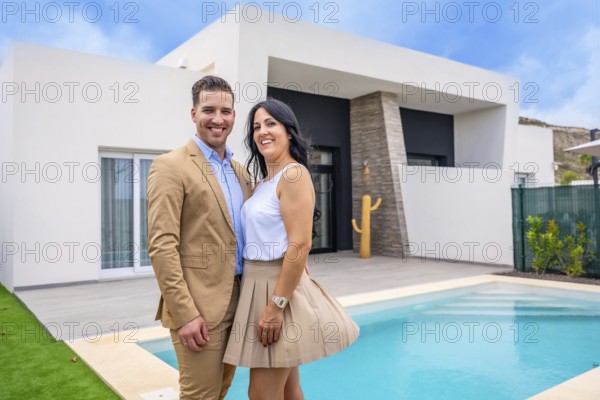Portrait of a happy couple standing on the pool of their new luxury home