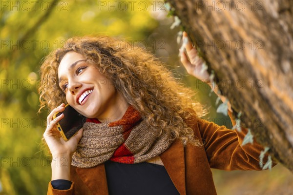 Beauty woman talking to the mobile in a park in autumn