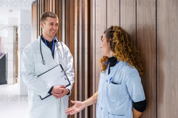 Team work of a female nurse and doctor talking in the corridor of an hospital