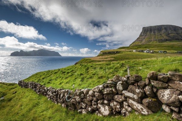 View of the island of Mykines, old stone wall, Gásadalur village, Vágar, Faroe Islands, Denmark, Europe