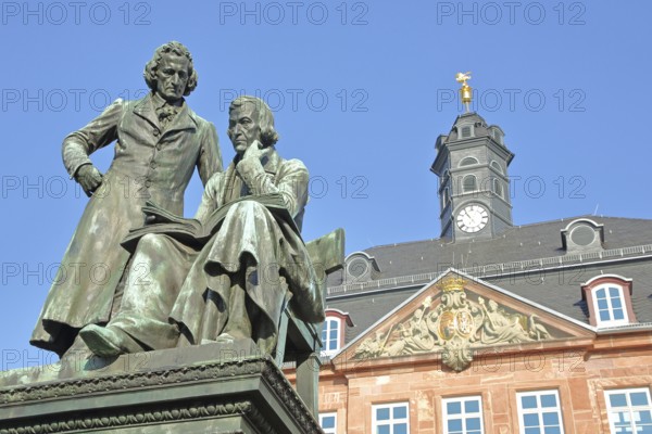 Brothers Grimm national monument, standing Jacob and sitting on the chair Wilhelm and baroque Neustadt town hall, brothers, bronze sculpture, poet, two, book, reading, German Fairy Tale Route, market square, Hanau, Hesse, Germany, Europe