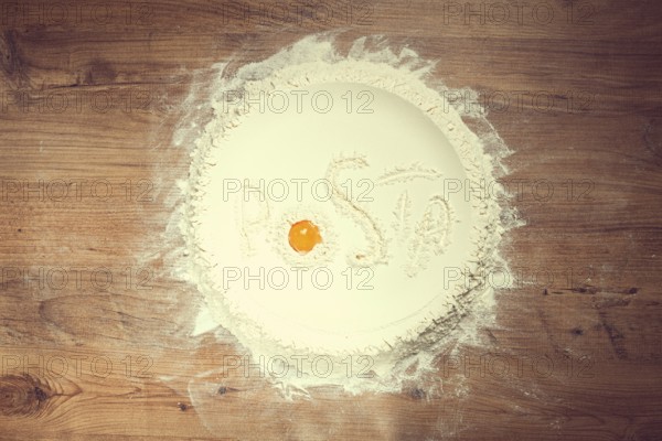 Flour on a wooden table, top view, inscription Pasta, with egg yolk, cooking, food concept, no people