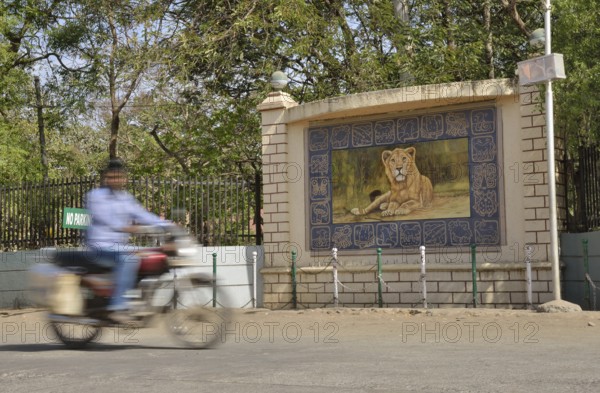 Motorcycle in front of the image of a lion, Asiatic Lion, outside the headquarters of the Forestry Commission, Gir Forest National Park, Gir Sanctuary, Sasan Gir, Gujarat, India, Asia
