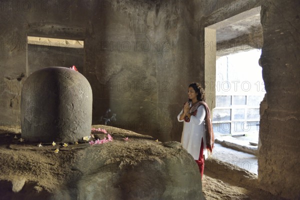 Woman praying in front of the Shiva Lingam, a phallic symbol, in the main cave of the Shiva temple, UNESCO World Heritage Site, Elephanta, Maharashtra, India, Asia
