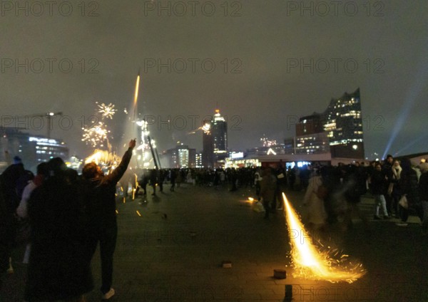 Person launches firework rocket from his hand, New Year's Eve 2025 on the Elbe promenade in Hamburg, at the harbour, on the Elbe, fire brigade of many thousands of people, Jan Fedder promenade