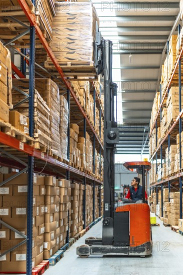 Vertical full length photo of a latin man worker driving forklift in a warehouse