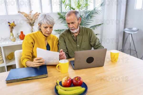 Paperwork in the living room where a senior couple with laptop for finance planning with retirement and pension fund