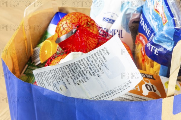 Symbolic image of food prices: Shopping bag full of groceries with a receipt