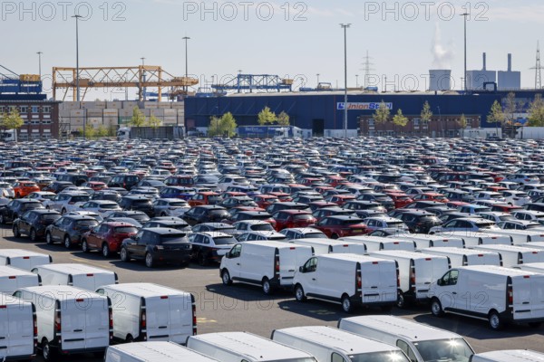 Duisburg, North Rhine-Westphalia, Germany - New cars and vans, car terminal in Duisburg harbour, cranes in the container harbour behind
