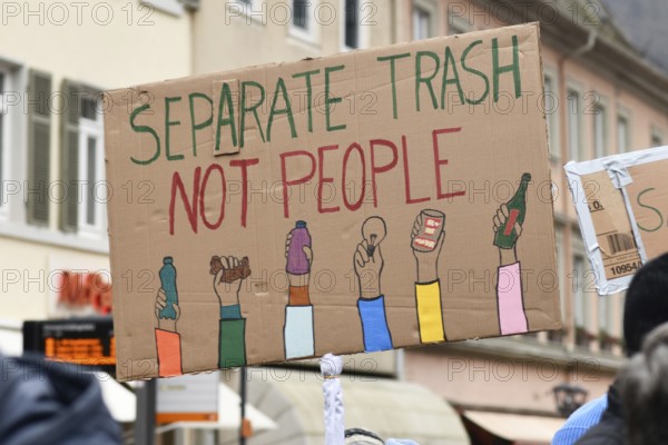Heidelberg, Germany - February 12th 2025: Person holding up sign with text 'Separate trash not people' in crowd at protest against far-right