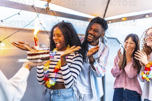 Multiracial young group of friends at terrace together celebrating with sparkling lights a summer birthday party