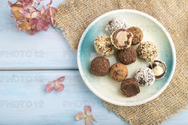 Chocolate truffle candies with cup of coffee on a blue wooden background and linen textile. top view, flat lay, close up