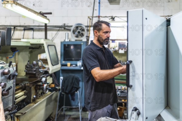 Mature caucasian male operator working in the control panel of cnc factory