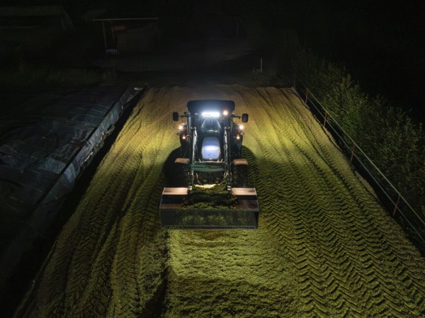 Tractor at night working on a silo filled with crop, maize harvest, Dachtel, Black Forest, Germany, Europe