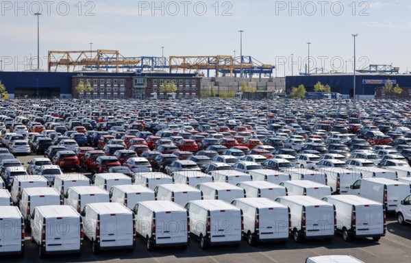 Duisburg, North Rhine-Westphalia, Germany - New cars and vans, car terminal in Duisburg harbour, cranes in the container harbour behind