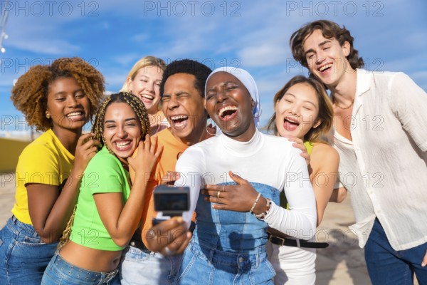 Muslim african woman taking a selfie while laughing with multi-ethnic and transgender friends