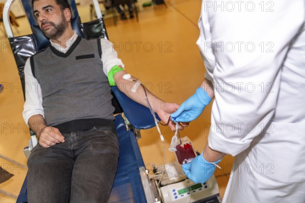 Unrecognizable female doctor collecting blood from a male donor into a bag