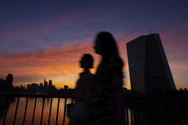 The light of the setting sun colours the sky behind the European Central Bank (ECB) and the Frankfurt skyline orange-red, Frankfurt am Main, Hesse, Germany, Europe