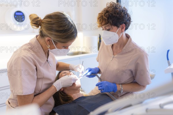 Dentist and assistant performing a filling on a tooth for a client in the modern dental clinic