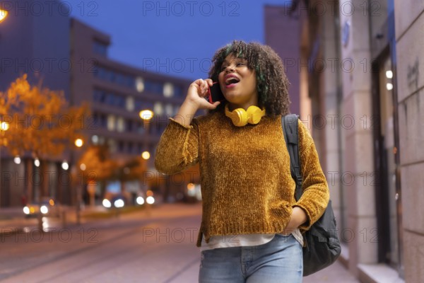 Portrait of black ethnic girl in the early morning going to the university on the way back to school talking on the phone